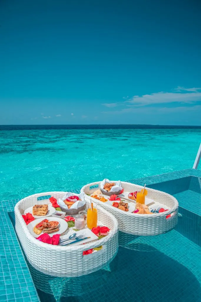 Breakfast trays floating in a turquoise pool by the sea